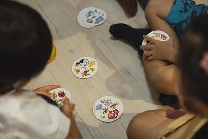 children sitting on the floor and playing a printed card game